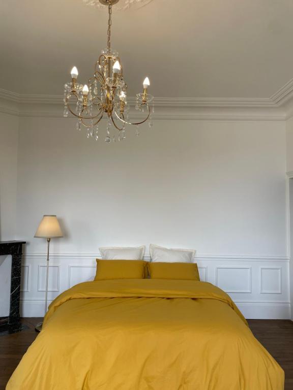 une chambre avec un lit jaune avec un lustre dans l'établissement Suite privative au Domaine des Étoiles du Gâtinais, à La Celle-sous-Gouzon