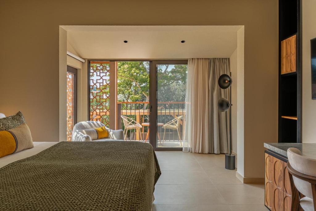 een slaapkamer met een bed en een balkon bij Eleonas Boutique Hotel & Spa - Adults Only in Ialyssos