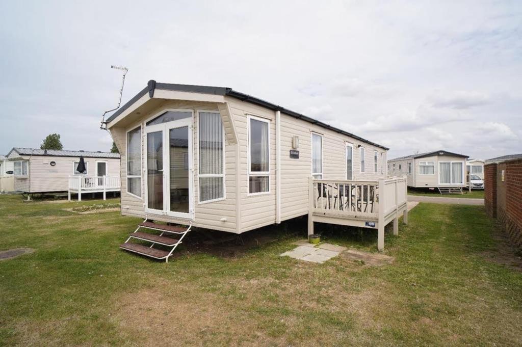 ein kleines Haus in einem Hof mit einer Veranda in der Unterkunft Tranquil 3Bedroom Caravan Pets stay Free in Hunstanton