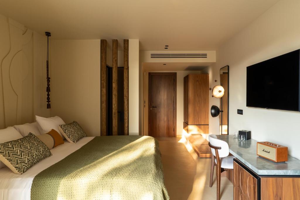 een slaapkamer met een bed, een bureau en een televisie bij Eleonas Boutique Hotel & Spa - Adults Only in Ialyssos