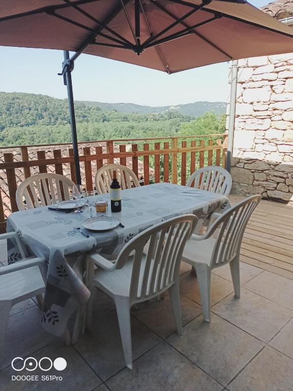 une table avec des chaises et un parasol sur une terrasse dans l'établissement Maison Les Glycines, à La Roque-Gageac