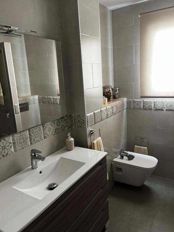 a bathroom with a sink and a toilet and a mirror at La terraza de la subbética in Luque