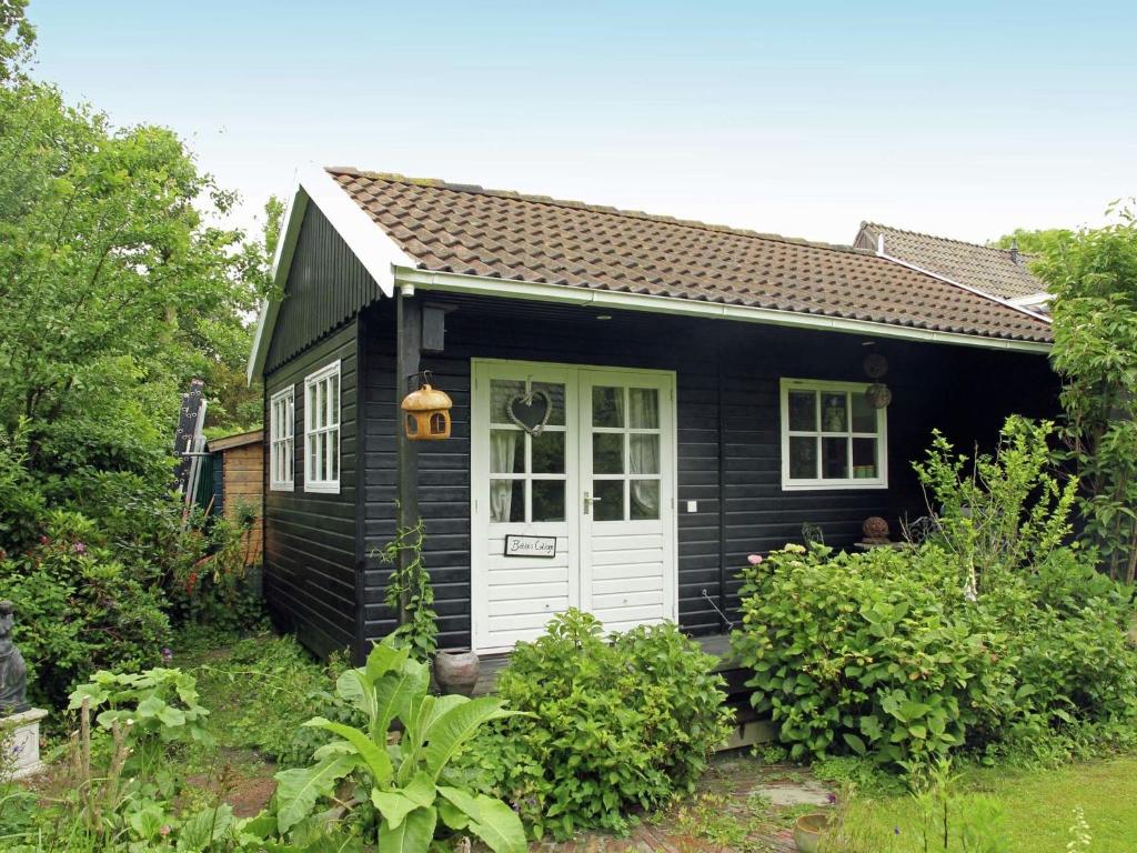 ベルゲンにあるRomantic Cottage in Bergen North Holland with terraceの白い扉のある小さな黒い家