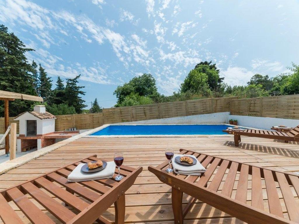 a wooden deck with a table and a swimming pool at Antica holiday house with pool, sea view in Savar