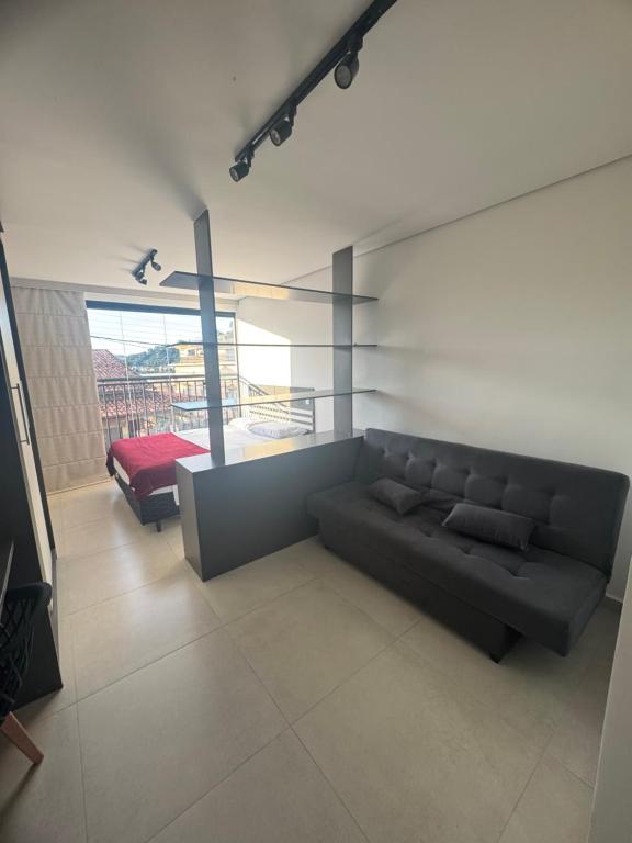 salon z czarną kanapą i łóżkiem w obiekcie Studio lindo com ar condicionado e piscina - Bela Vita - 104 w mieście São Lourenço