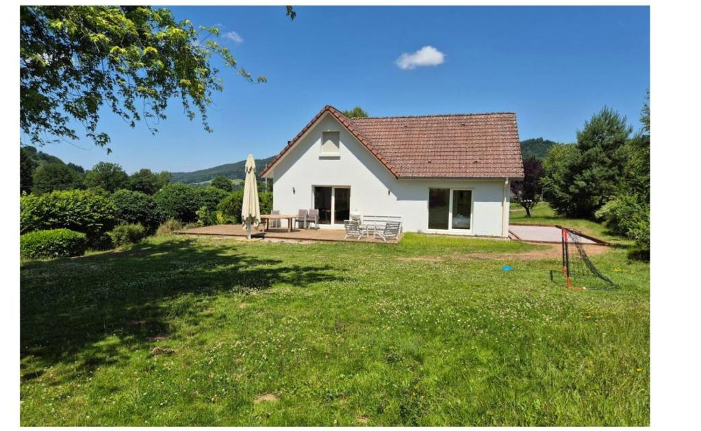 une petite maison blanche avec une grande cour avec un champ herbeux dans l'établissement La Ribambelle - Terrain de pétanque et barbecue, à Tendon