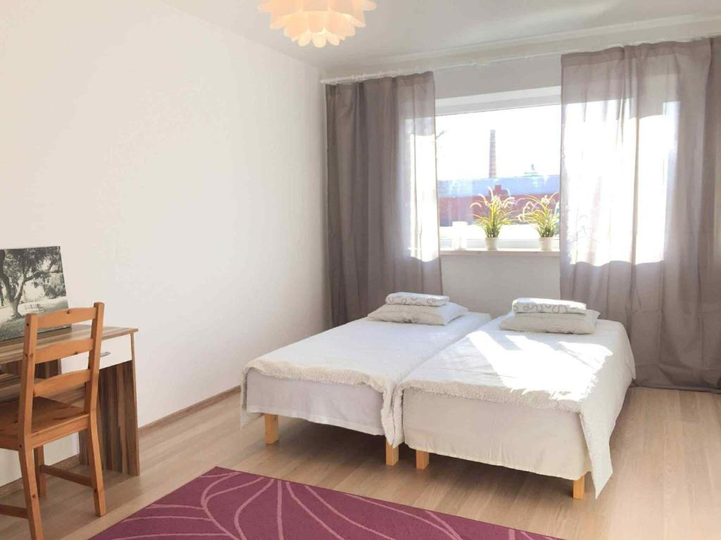 a bedroom with two beds and a desk and a window at Holiday apartment Helena in Kõrgessaare