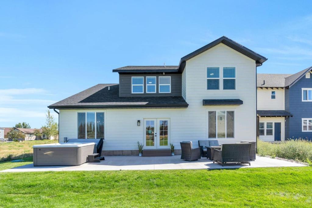 une maison blanche avec une terrasse et 2 chaises dans l'établissement Dream Bear Lake Getaway w/ Hot Tub & Yard, à Garden City