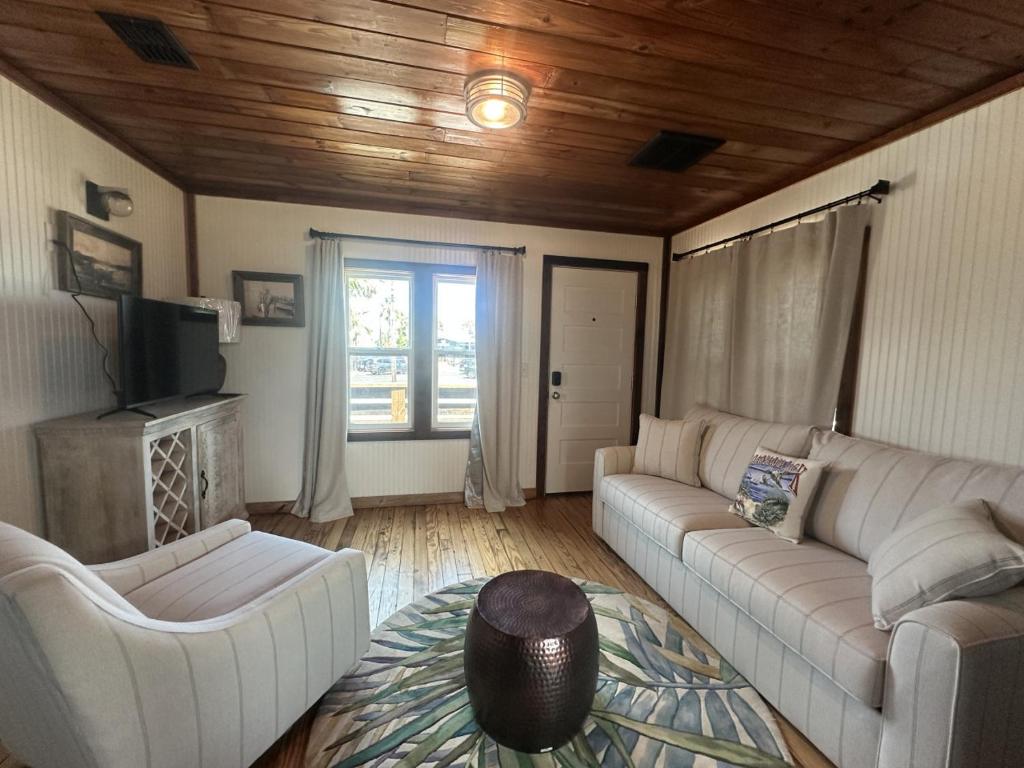 ein Wohnzimmer mit zwei Sofas und einem Fernseher in der Unterkunft The Historic Gibbs Cottages 7 in Port Aransas