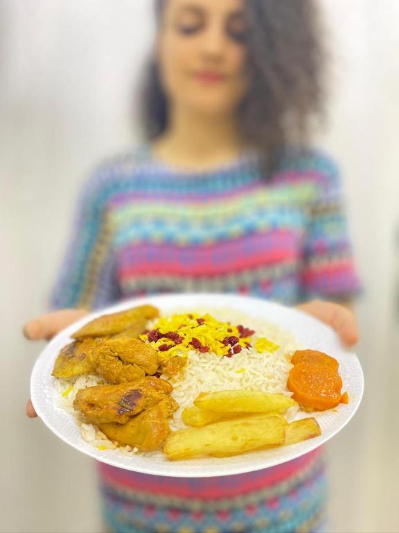 una ragazza che tiene in mano un piatto di cibo su un piatto di Hostel mahsa a Mascate