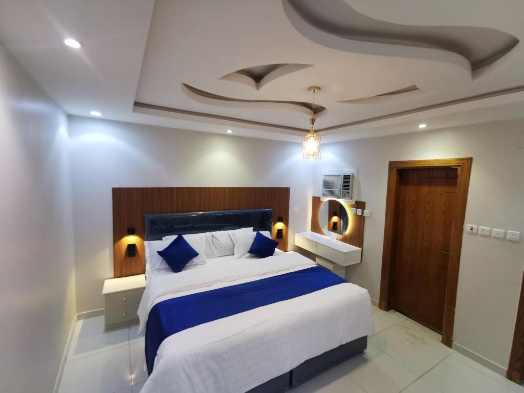 a bedroom with a large bed with blue and white sheets at شوران الأولى in Al Madinah