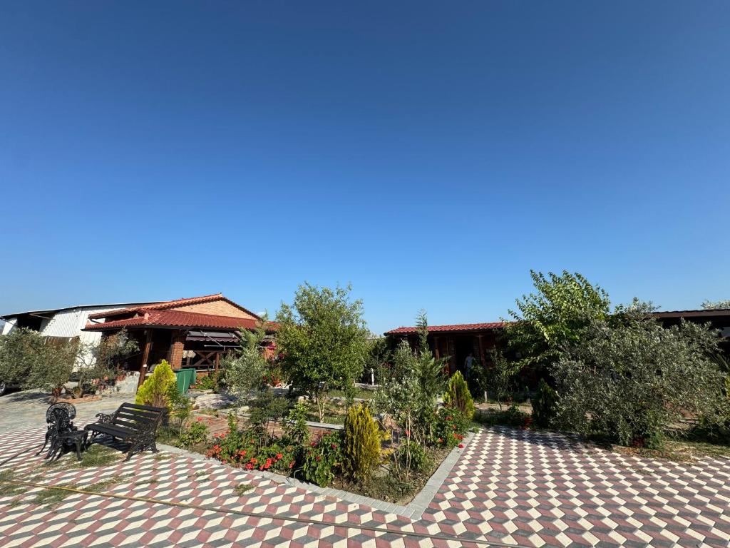 a park with a bench and flowers in front of a building at Golden Campsite Villas in Berat
