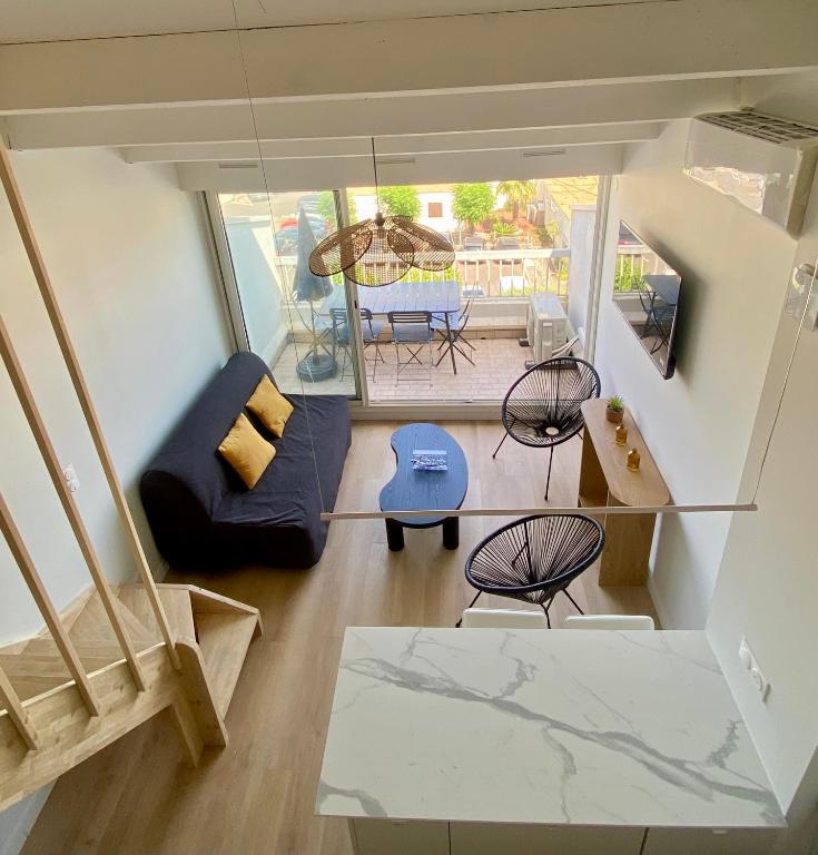 une vue aérienne d'un salon avec un canapé et des chaises dans l'établissement Village naturiste Appart B Port Soleil, au Cap d'Agde