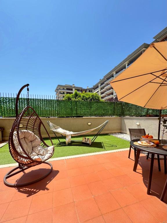 a patio with a hammock and a table with an umbrella at Sun Nest Apartment - terrace & garage in Fiumicino