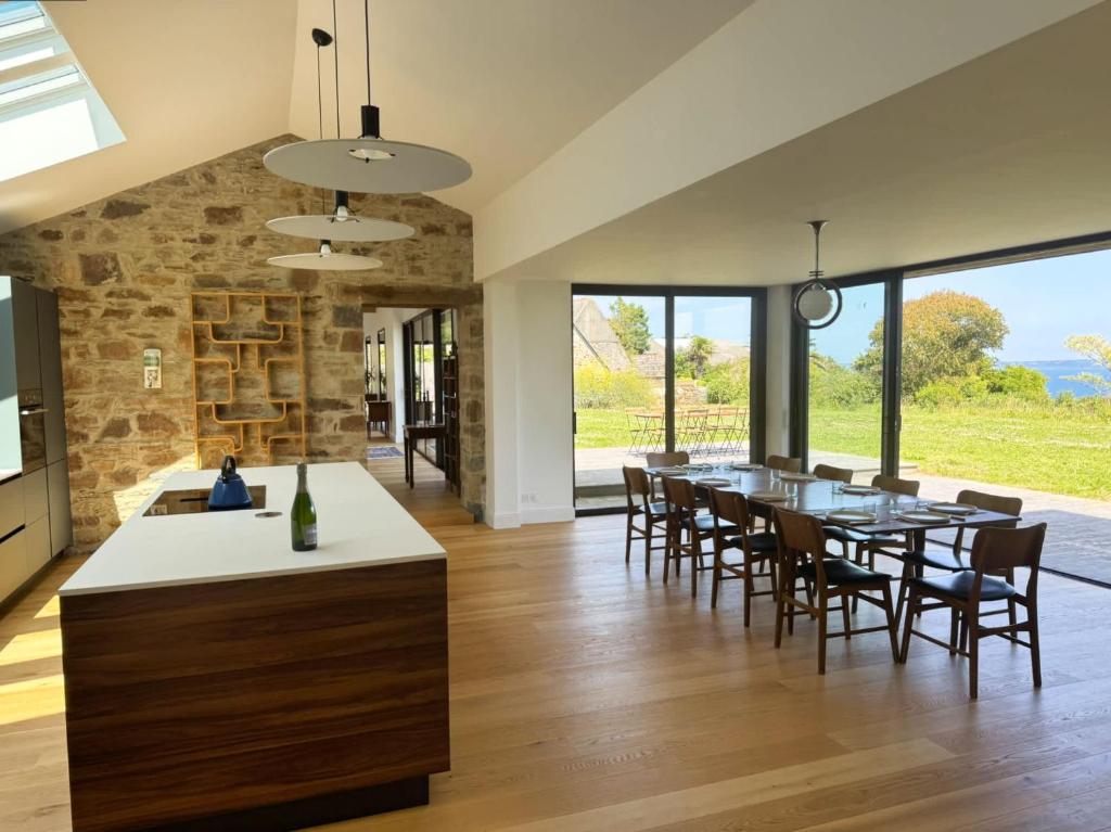 a kitchen and dining room with a table and chairs at Villa Les Embruns sea view Beg Ar Fry 10 people in Guimaëc