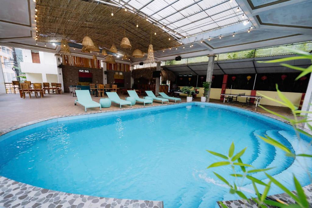 a large pool in a hotel with chairs and tables at Ha Giang Loop Rabbit Hostel & Tours in Ha Giang