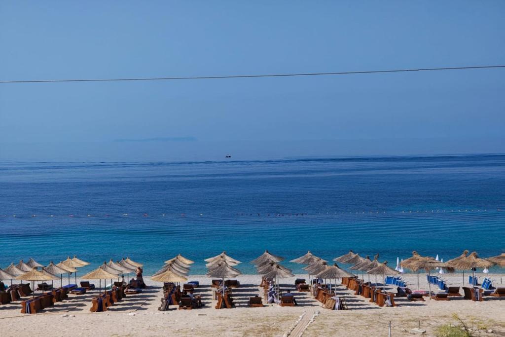 a beach with chairs and umbrellas and the ocean at Anxhelos Hotel in Himare