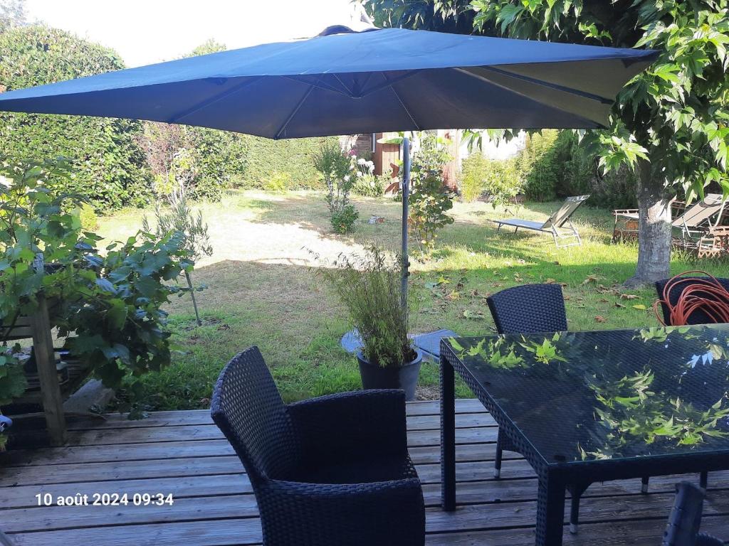 a patio with an umbrella and chairs and a table at VILLA DE PLAIN PIED ET STUDIO CLIMATISES, AU CALME, 6 PERSONNES MAXIMUM A 7mn DU GOLF ET DE LA PLAGE in Seignosse