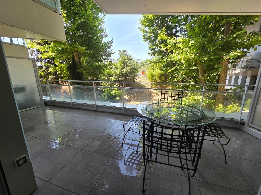d'une terrasse avec une table en verre et des chaises sur un balcon. dans l'établissement T2 avec parking aux portes de montpellier, à Castelnau-le-Lez