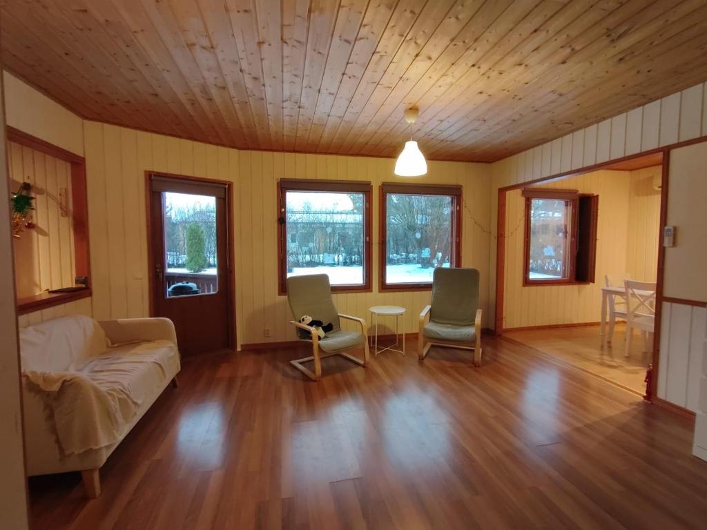 Una sala de estar con un sofá y sillas y ventanas. en Artjarvi Center Art Villa vacation house, en Artjärvi