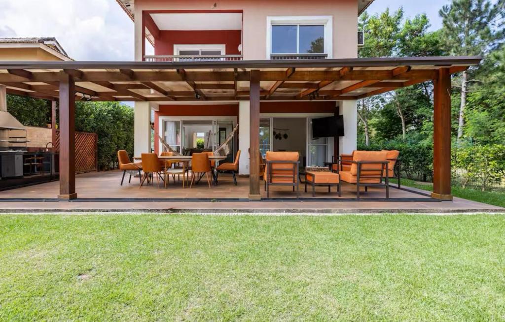 eine Terrasse mit Tisch und Stühlen unter einer Pergola in der Unterkunft Melhor casa Praia na Reserva do Sahy in Mangaratiba