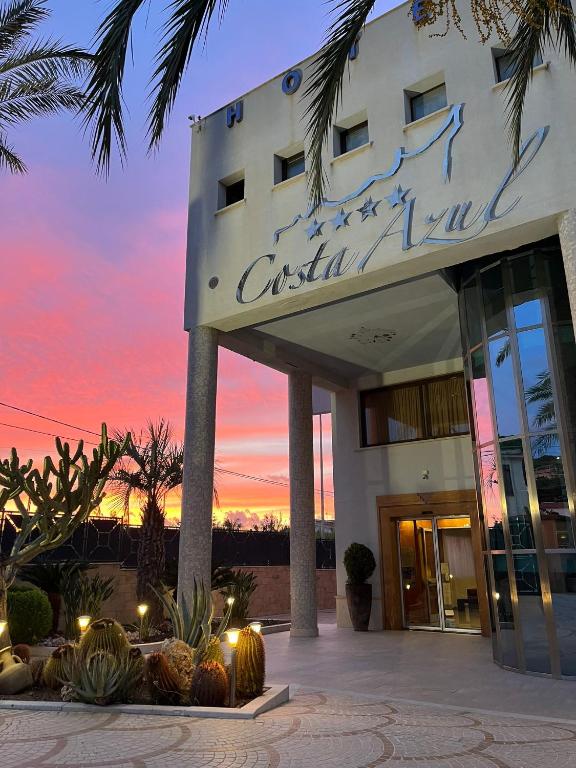 a building with a sign in front of a sunset at Hotel Costa Azul in Balestrate