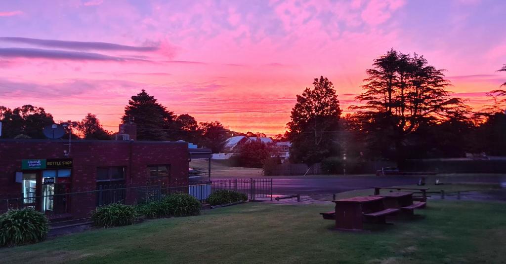 a sunset over a park with benches and a building at Dartmoor Hotel Motel in Dartmoor