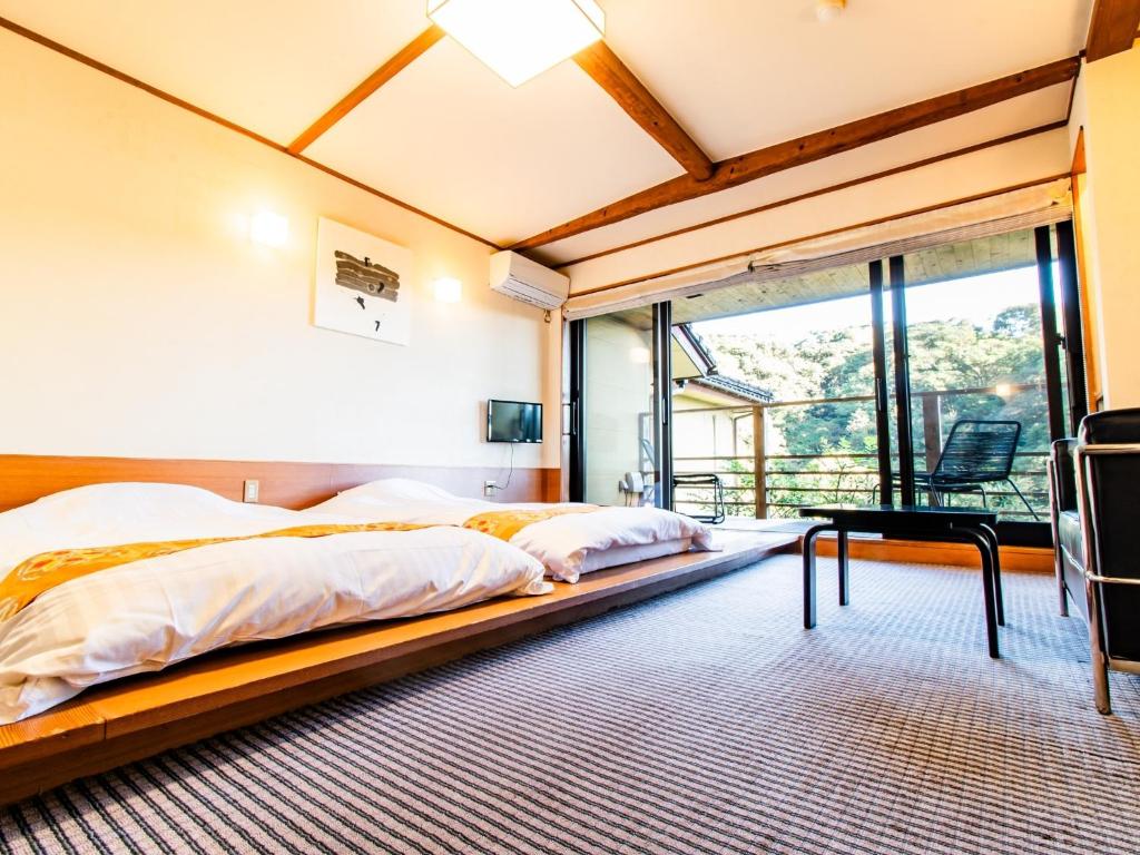 two beds in a room with a large window at Kirishima Momijidani Seiryuso - Vacation STAY 63072v in Kirishima