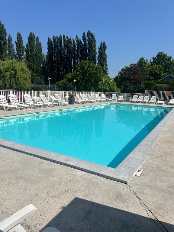 a large swimming pool with lounge chairs around it at Cozy bungalow in Ivry-la-Bataille