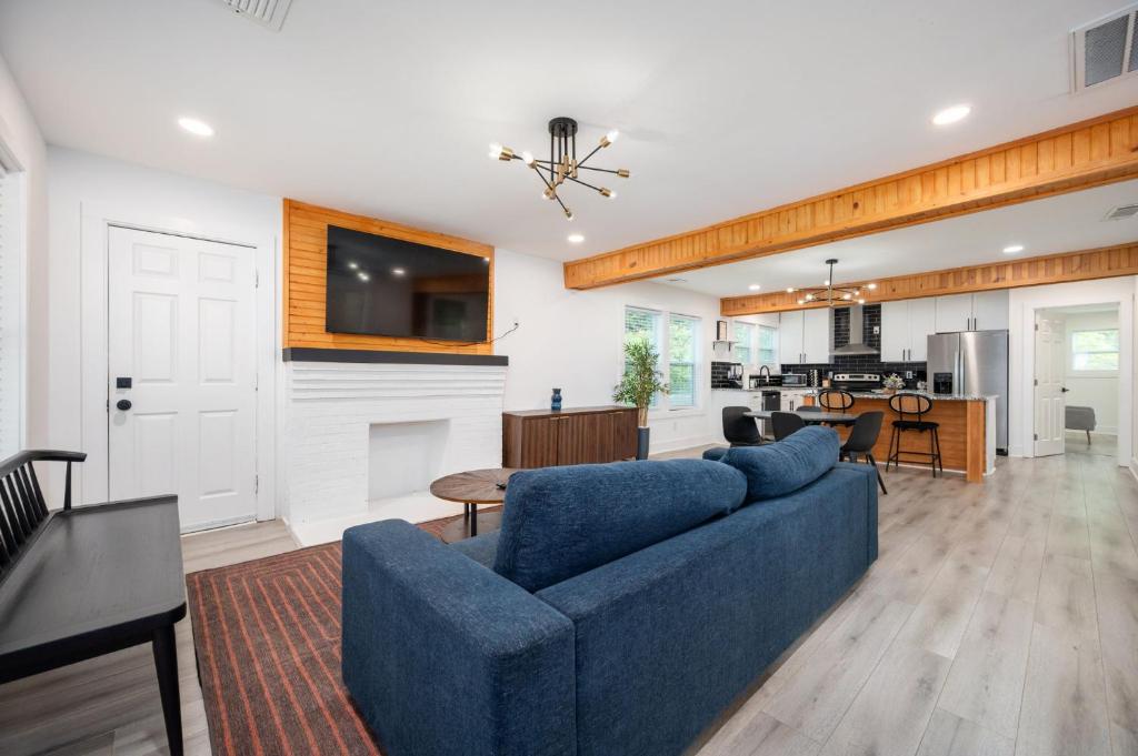 Una sala de estar con un sofá azul y una cocina. en Chic 3BR Bungalow with Screened Porch & Patios, en Atlanta