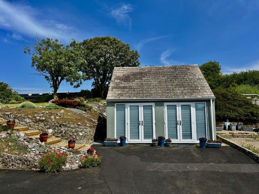 ein kleines Haus mit einer Veranda und einigen Pflanzen in der Unterkunft Tower Cottage in Pembroke