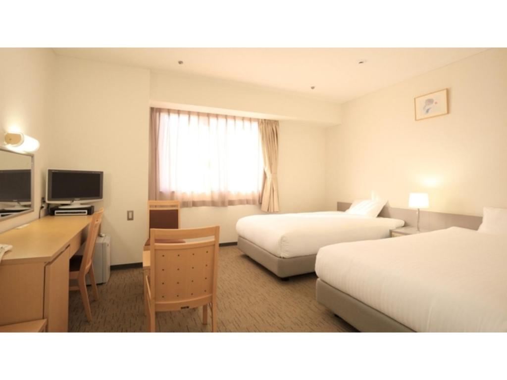 a hotel room with two beds and a desk at Smile Hotel Hirosaki - Vacation STAY 40511v in Hirosaki
