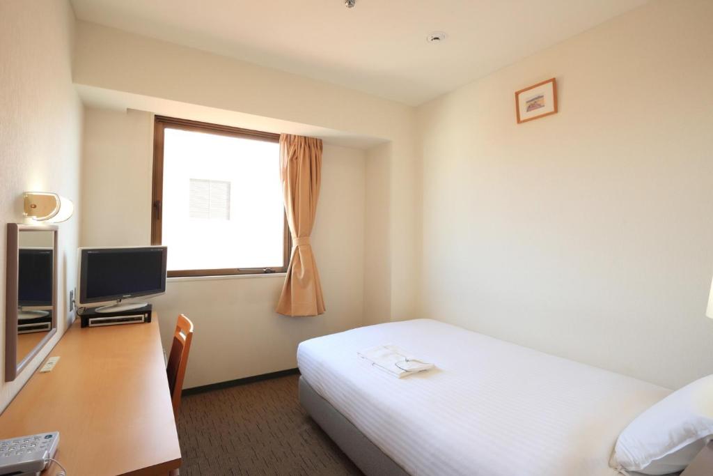 a hotel room with a bed and a desk and a window at Smile Hotel Hirosaki - Vacation STAY 40498v in Hirosaki