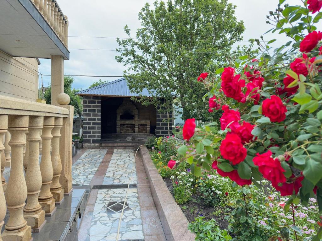 a garden with red roses in front of a building at Guest House Chkalovka Garden in Sevan