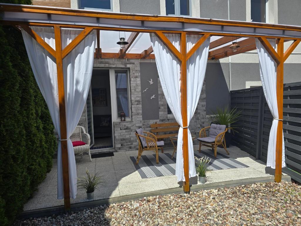 a pergola with white curtains on a patio at TROPIC-APARTAMENTY in Hel
