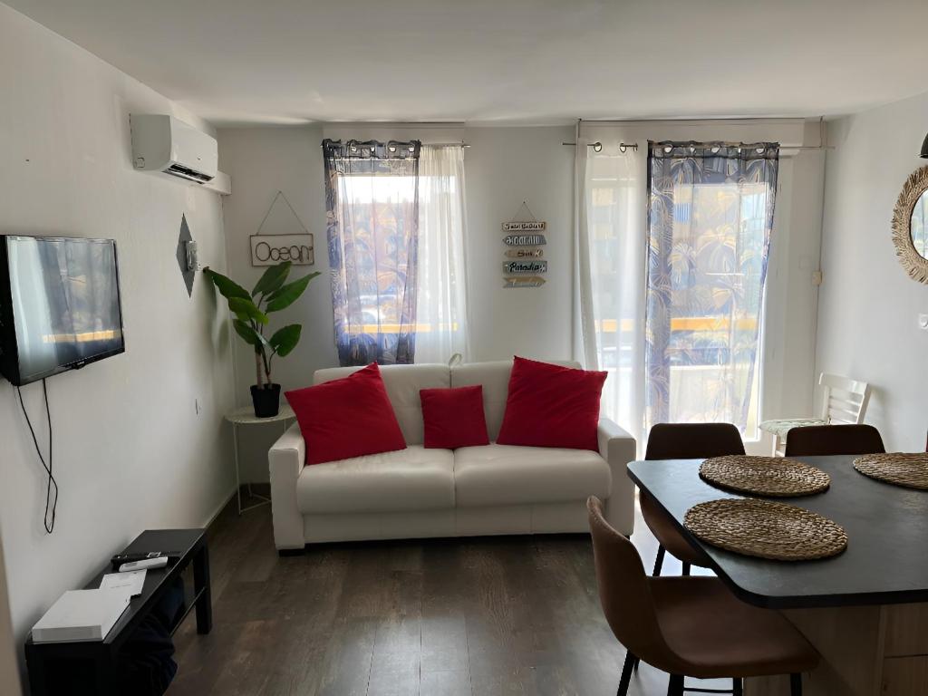 - un salon avec un canapé blanc et des oreillers rouges dans l'établissement Studio - Les Cigales De Mer - Centre Ville -100 m de la plage, au Grau-du-Roi