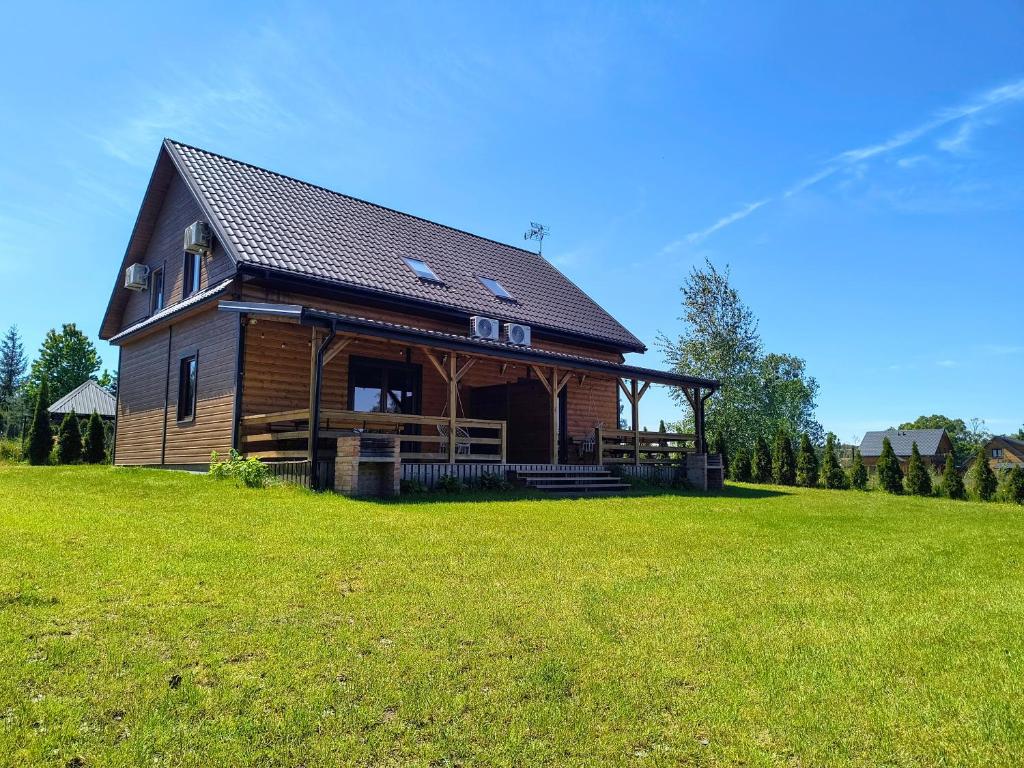 a log cabin on a grassy field with a house at Domki Apartamenty Ewelka in Okuninka