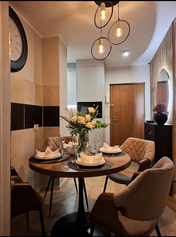 a dining room with a table and chairs and a clock at Apartament Alchemia Gór in Złoty Stok