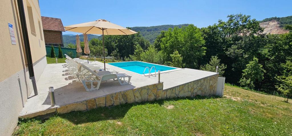 a pool with chairs and an umbrella next to a house at Villa Green Oasis Swimming Pool in Sarajevo