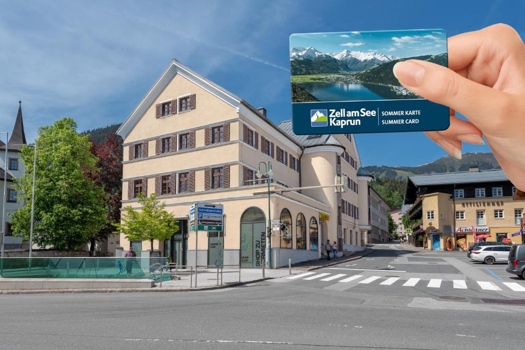 une main tenant une photo d'un bâtiment dans l'établissement Post Residence Apartments incl ZAK SUMMER CARD by All in One Apartments, à Zell am See