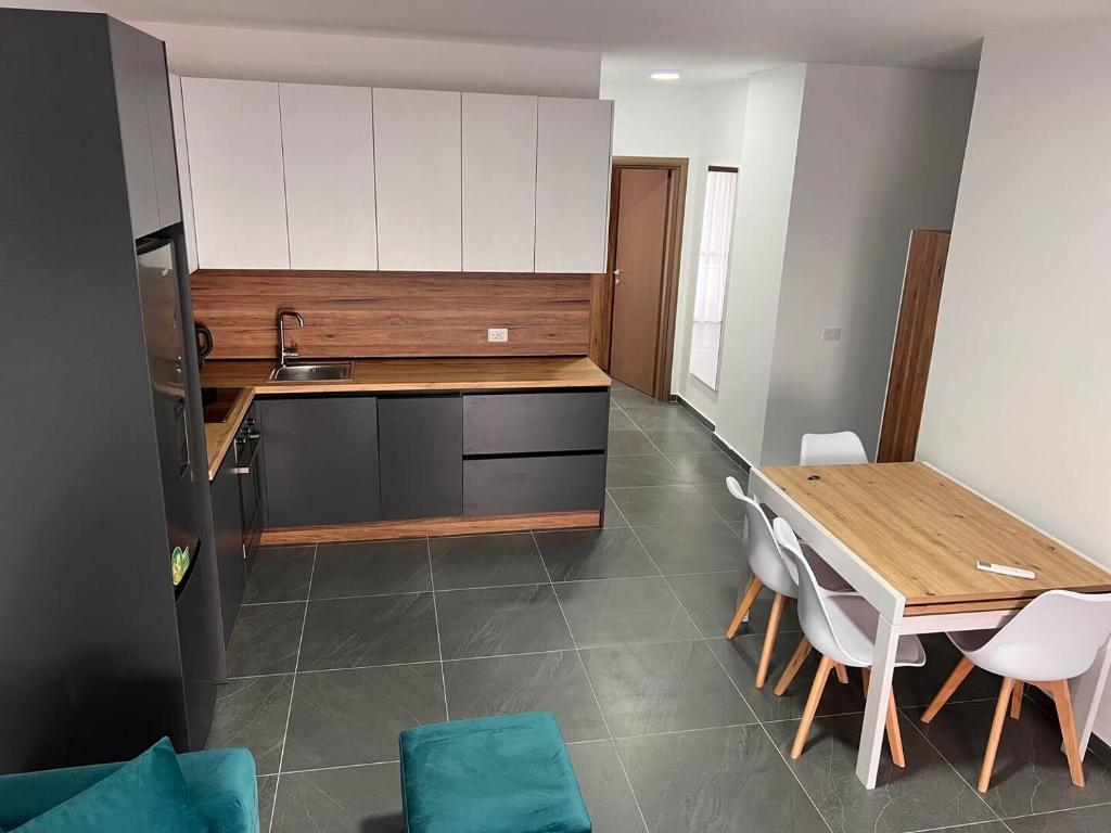 Blue Sapphire by Adriatic Living في Shkallnur: مطبخ مع طاولة خشبية ودواليب بيضاء