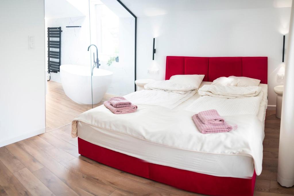 - une chambre avec un lit rouge et blanc et une baignoire dans l'établissement Willa Matejki - Apartament 8a, à Przemyśl