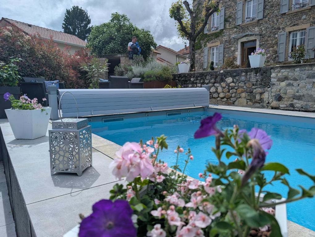 a swimming pool in a yard with flowers at La Maison d'Arlette - Maison d'Hôte et Gite au coeur de l'Isère à 10 mn de Voiron, capitale de la Chartreuse, et du Lac de Paladru in Saint-Blaise-du-Buis
