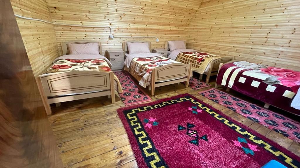 tre letti in una stanza di legno con un tappeto di Hotel-Restorant Pepushaj a Shkodër