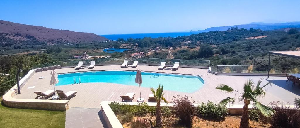 a swimming pool with chairs and a view of a mountain at Villa Lefkothea in Georgioupoli