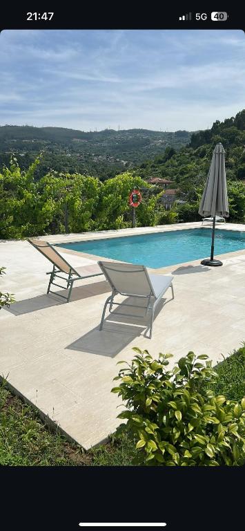 a swimming pool with two chairs and an umbrella at Quinta da Travessa in Cinfães