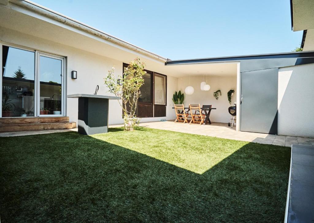een achtertuin met groen gras en een huis bij Matic Murgle Atrium Apartment in Ljubljana