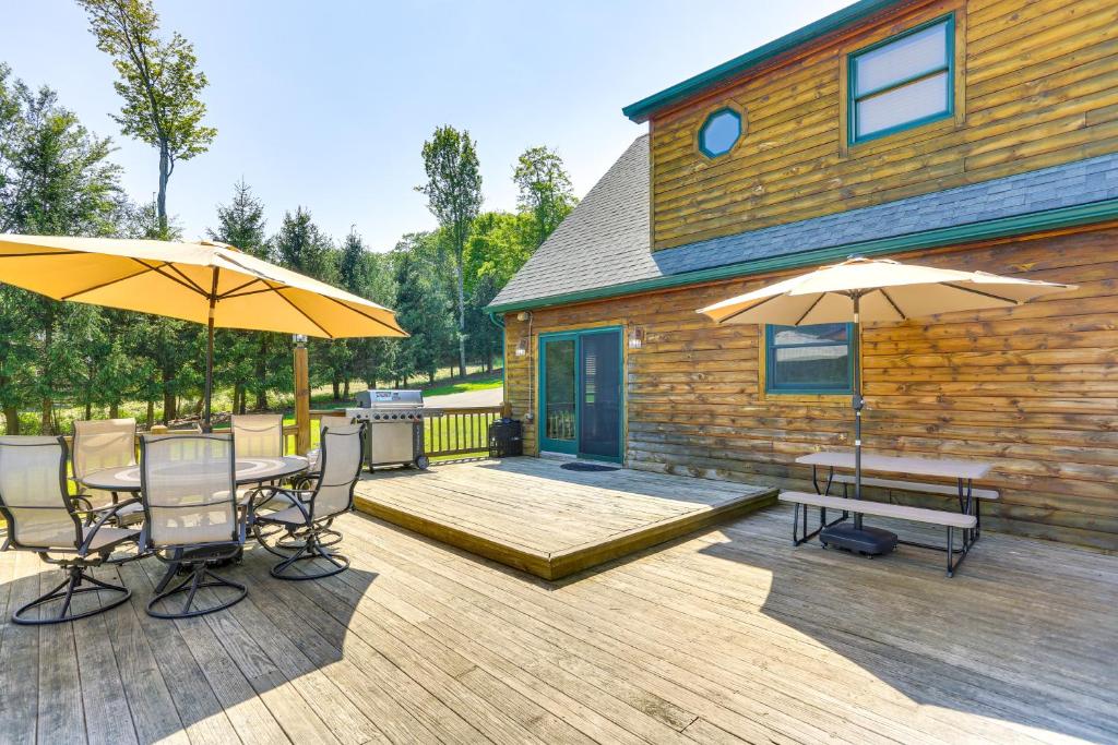 a wooden deck with two tables and two umbrellas at Home Theater and Game Room Home in Glen Wild! in Glen Wild