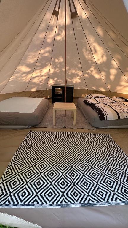 a room with two beds and a table in a tent at Glamping Stodoła Tent in Ściegny