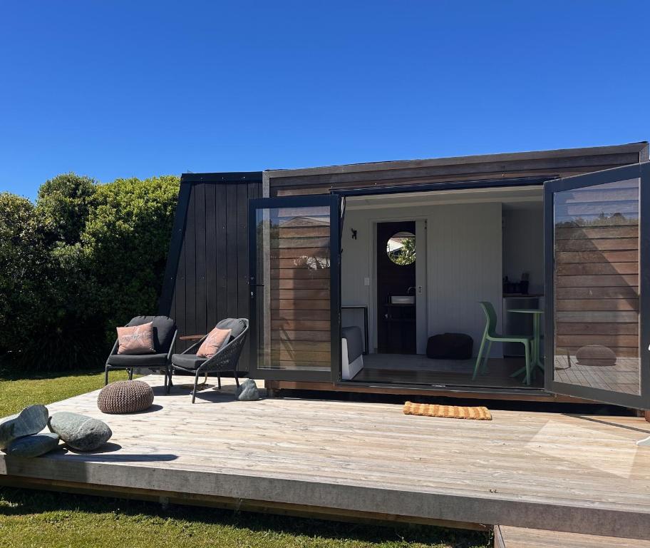 a tiny house with a deck and two chairs at The Wee Snug in Hokitika